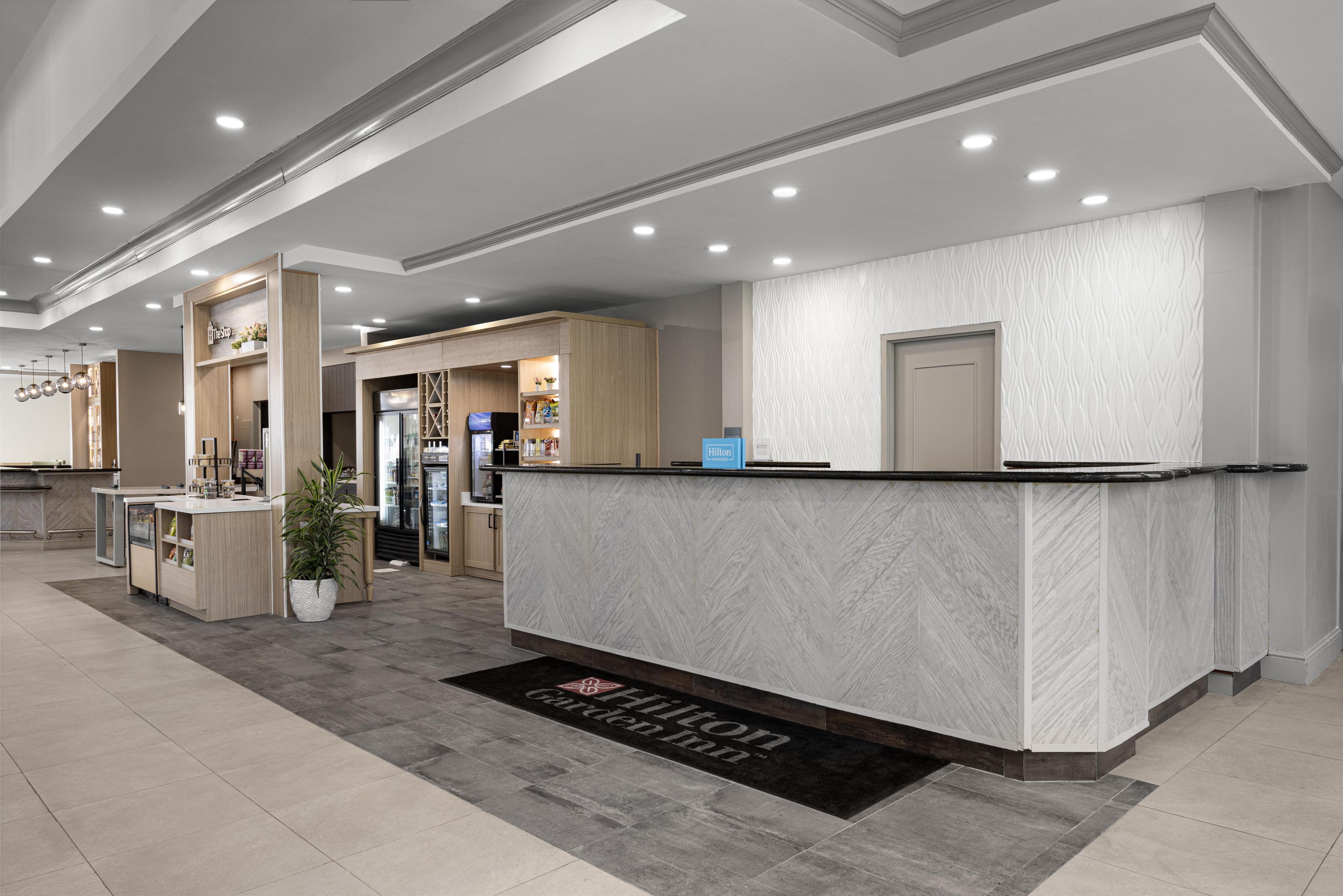 A hotel reception area with a marble counter, a reception desk, a plant, and a sign indicating the hotel's name.