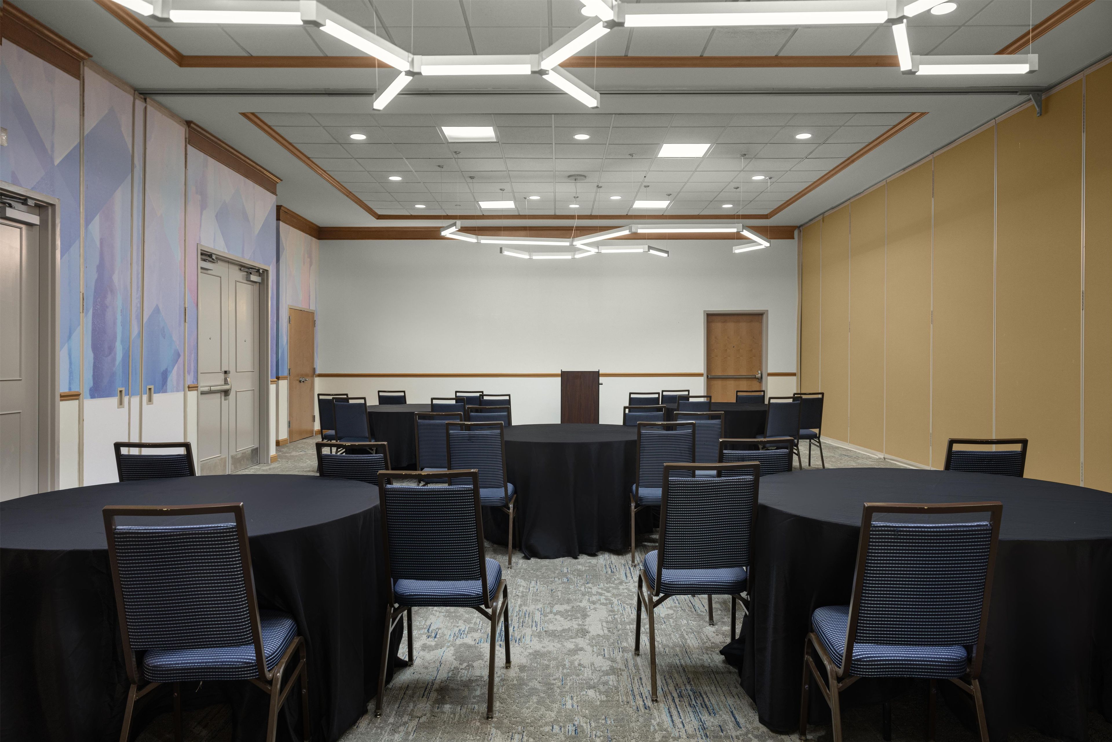 Une salle de conférence avec des tables rondes, des chaises et un sol recouvert de moquette.