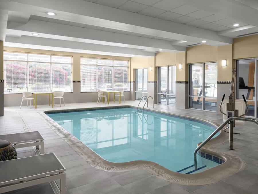 An indoor swimming pool with clear water, surrounded by a tiled floor, and equipped with a pool ladder.