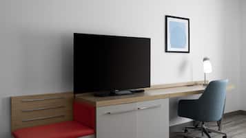 A modern hotel room with a flat-screen TV, a desk, a chair, and a bedside table.