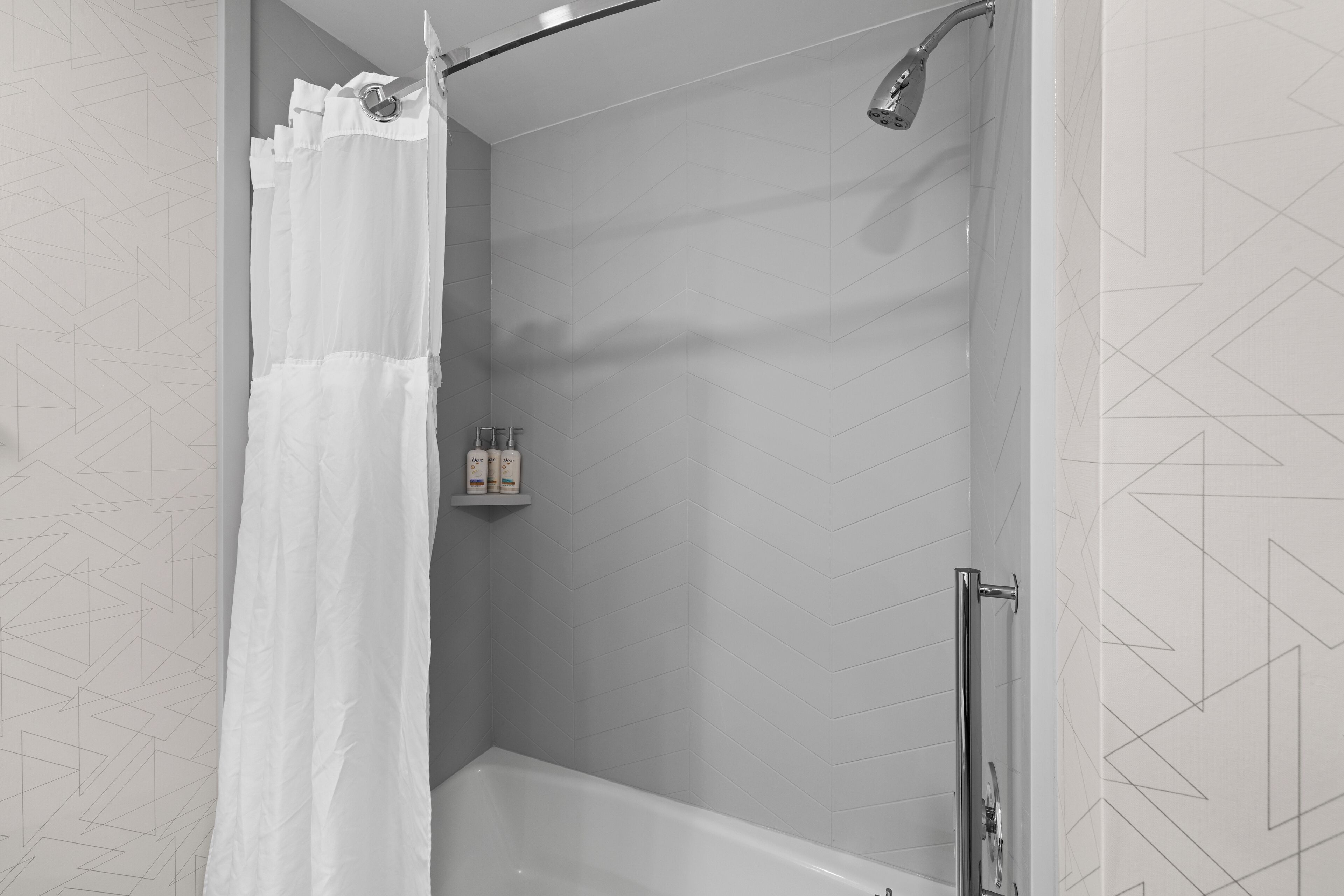 Eine moderne Dusche mit weißem Duschvorhang, einer Handbrause und einer Glastrennwand.