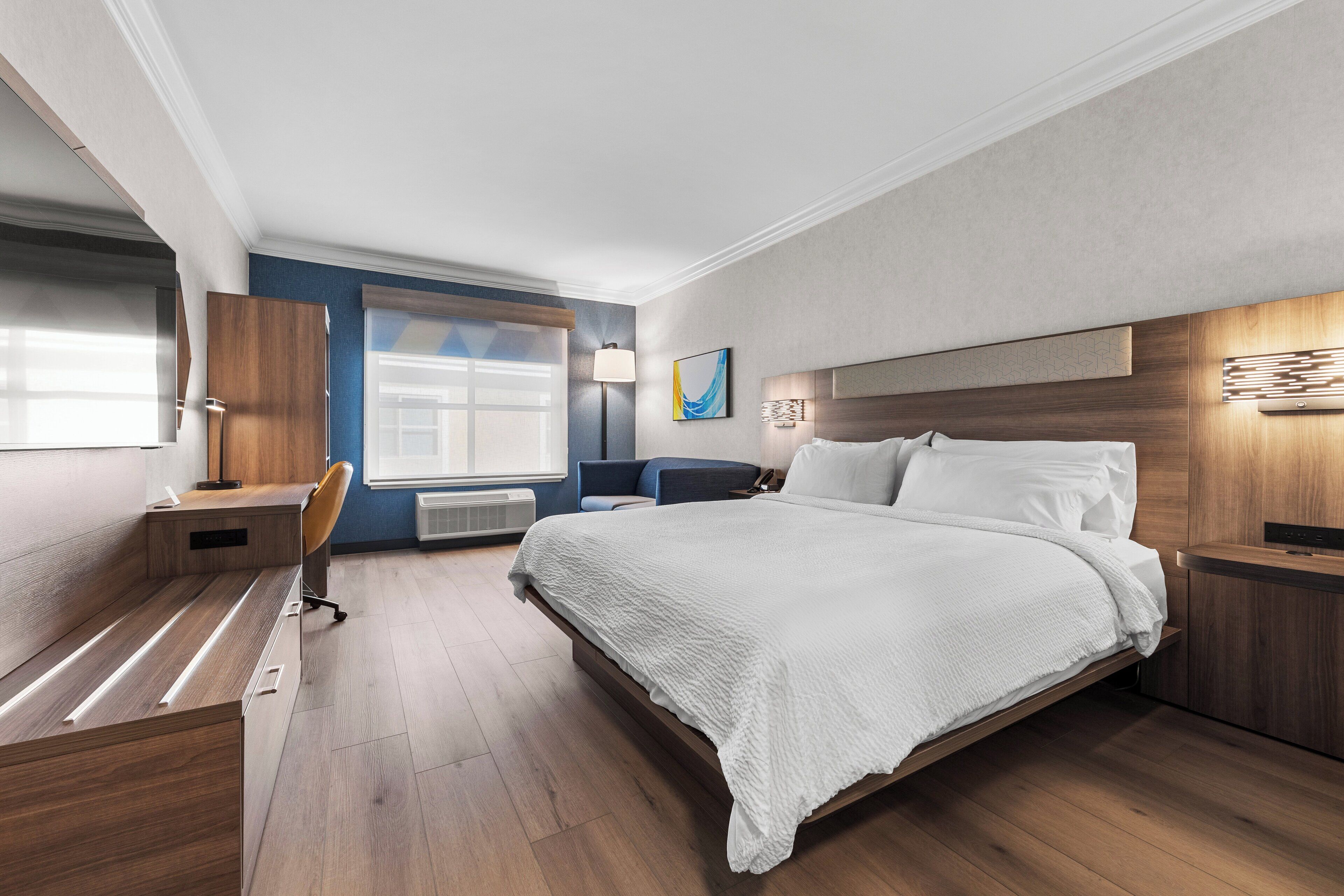 Una habitació d'hotel moderna amb un llit gran, una taula de treball i una cadira.