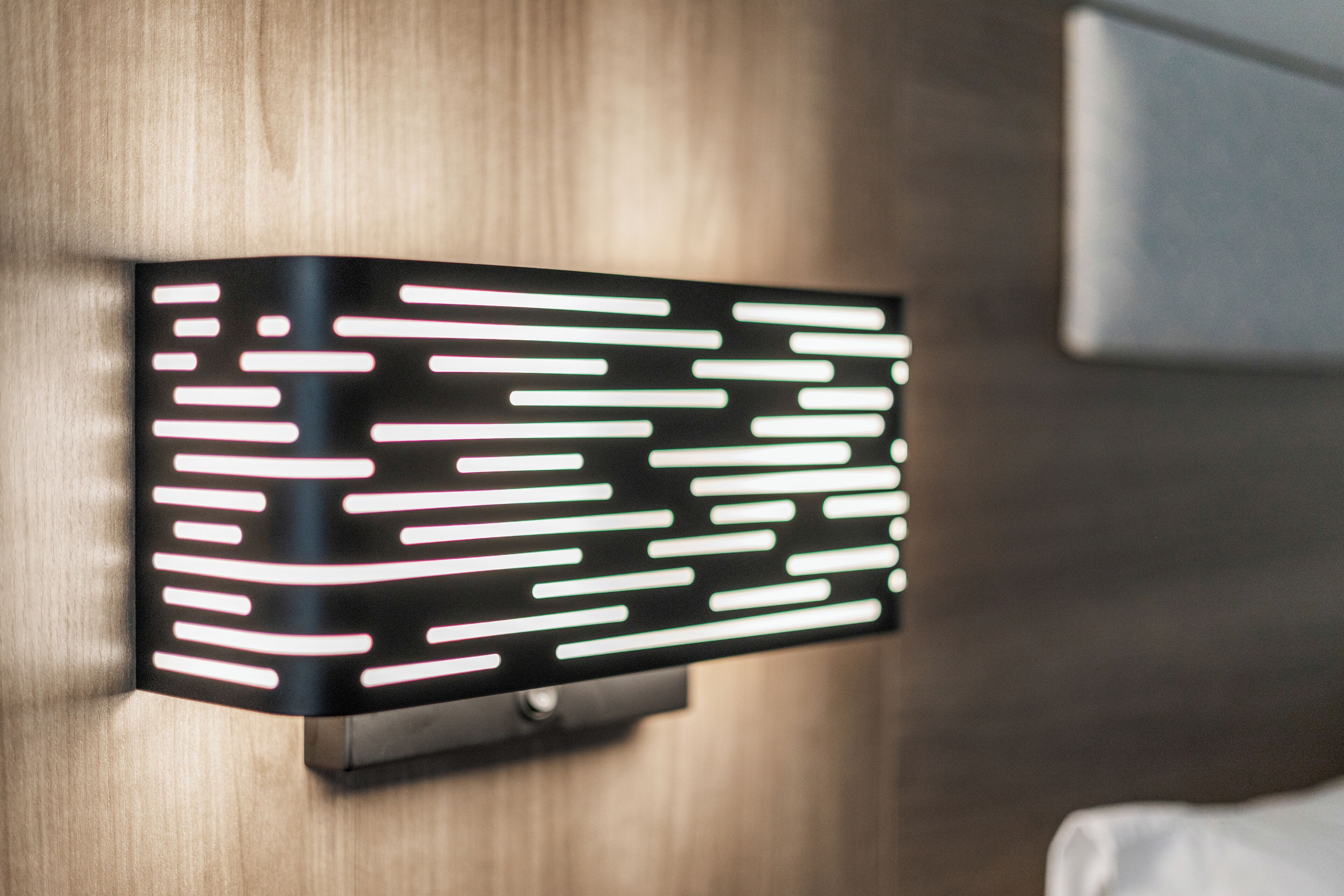 A modern wall-mounted light fixture with horizontal lines.
