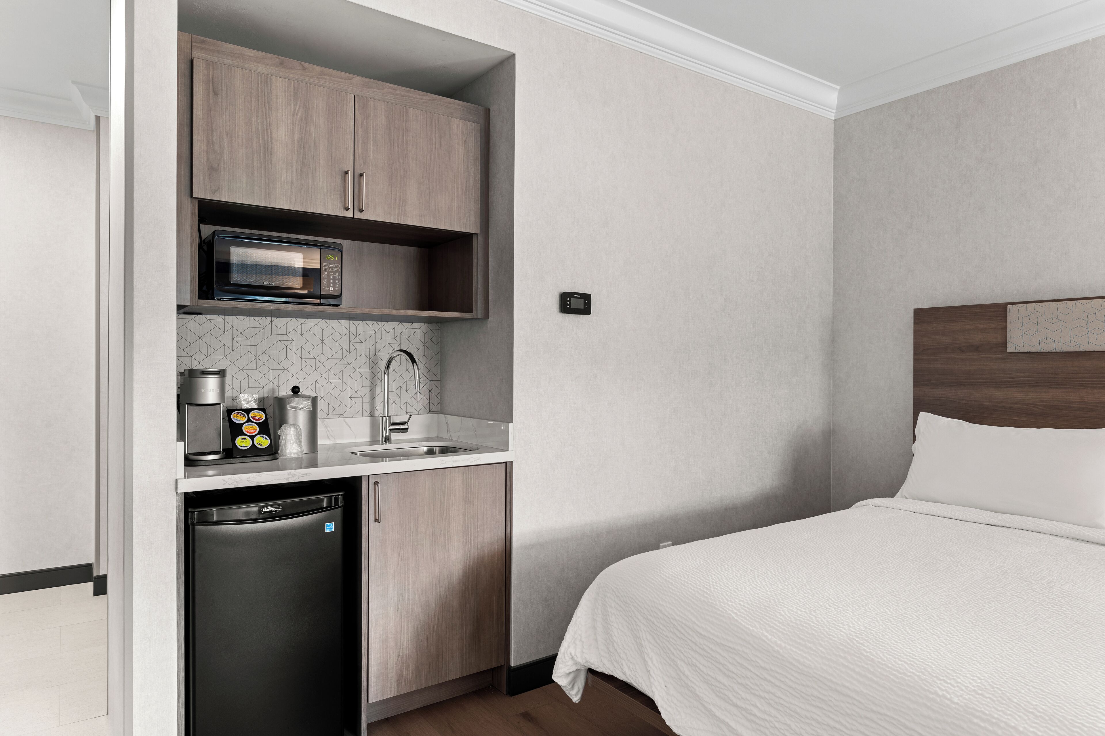 Camera d'albergo compatta con angolo cottura, dotata di forno a microonde, macchina del caffè e lavastoviglie.