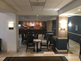Un hall de hotel con mostrador de recepción, zona de estar y alfombra estampada.