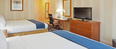 Une chambre d’hôtel avec deux lits, un bureau avec une chaise, une télévision et un miroir.