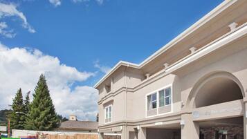 A Holiday Inn Express & Suites building with a clear sky, a gated entrance, and a landscaped area with plants.