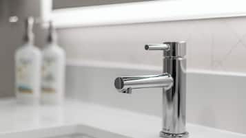 Un baño moderno con grifo cromado, encimera blanca y salpicadero de azulejos.
