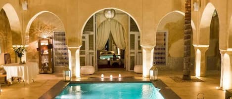 Een buitenzwembad, parasols bij het zwembad en ligstoelen