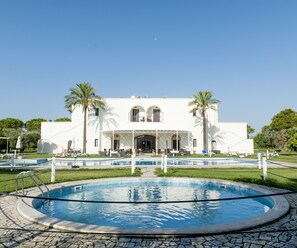 A white building with a pool in front.