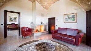 A spacious living room with a fireplace, a red leather sofa, and a patterned rug. - Masseria la Baronessa Resort (Tuglie)