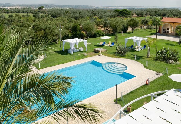 A swimming pool with a view of the countryside, surrounded by white canopies and lounge chairs. - Masseria la Baronessa Resort (Tuglie)