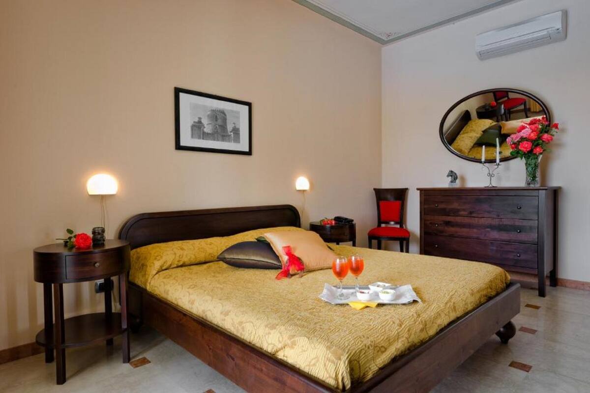 A neatly arranged bedroom with a bed, bedside tables, a dresser, a mirror, and a framed picture on the wall.