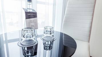 Una mesa con una botella de agua mineral Lux Hotels, dos vasos y una base de mesa negra.