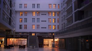 Ein mehrstöckiges Hotel mit einer zentralen Treppe, ein Restaurant namens 'Palatus' im Erdgeschoss und ein weiteres Restaurant 'Fatima' im zweiten Stock.