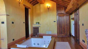 Une pièce spacieuse avec une grande baignoire, des poutres apparentes en bois au plafond et une cheminée.