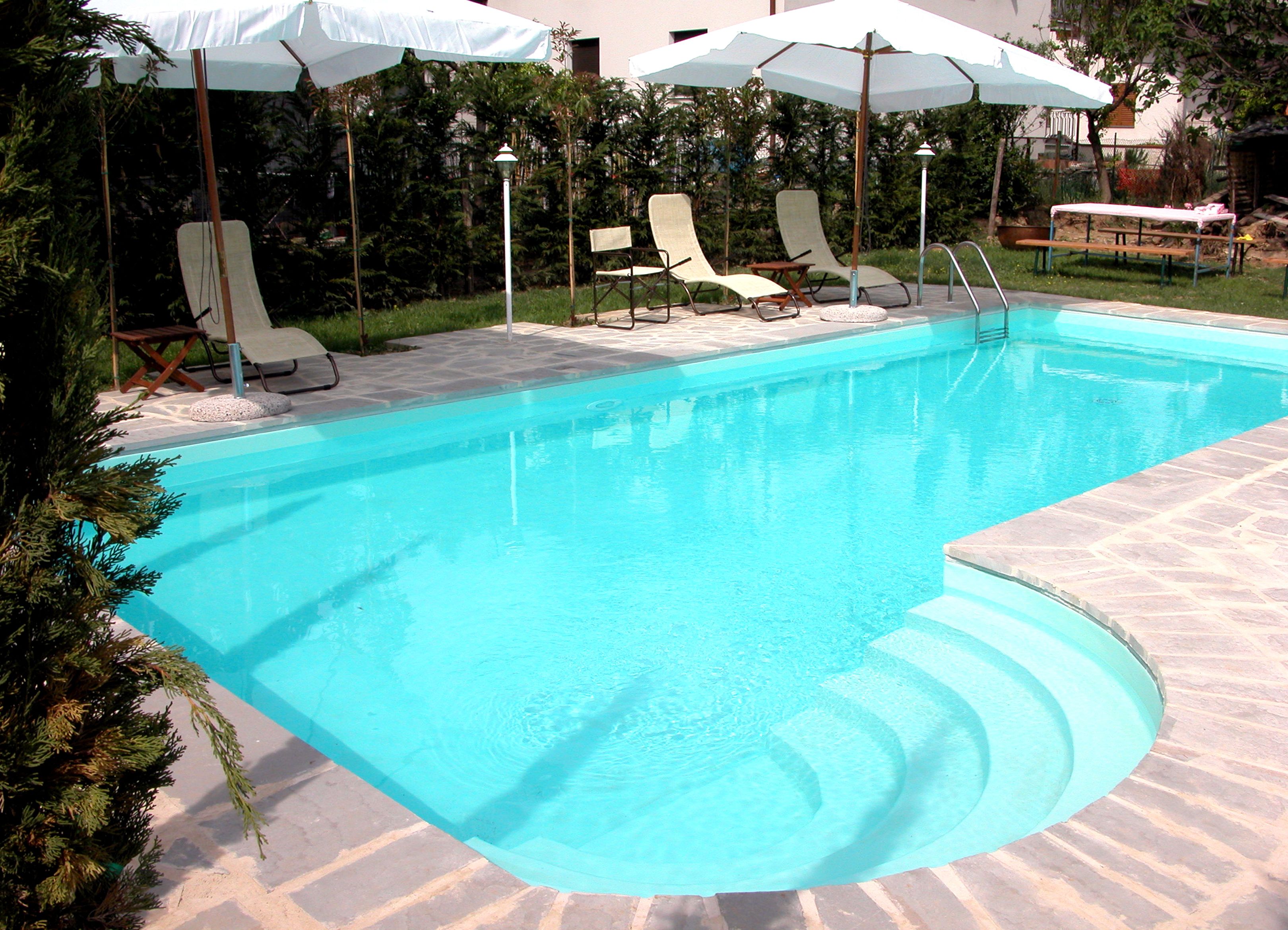 A swimming pool with lounge chairs and umbrellas.