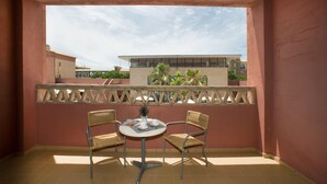 A balcony with two wicker chairs and a small round table, featuring a view of buildings and greenery. - Apartamentos Leo Punta Umbría (Punta Umbría)
