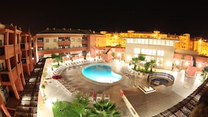 A hotel courtyard with a swimming pool, lounge chairs, and a covered seating area. - Apartamentos Leo Punta Umbría (Punta Umbría)