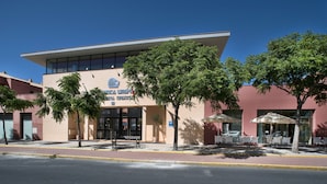 A modern building with a flat roof and large windows, featuring a sign with a logo and text. - Apartamentos Leo Punta Umbría (Punta Umbría)