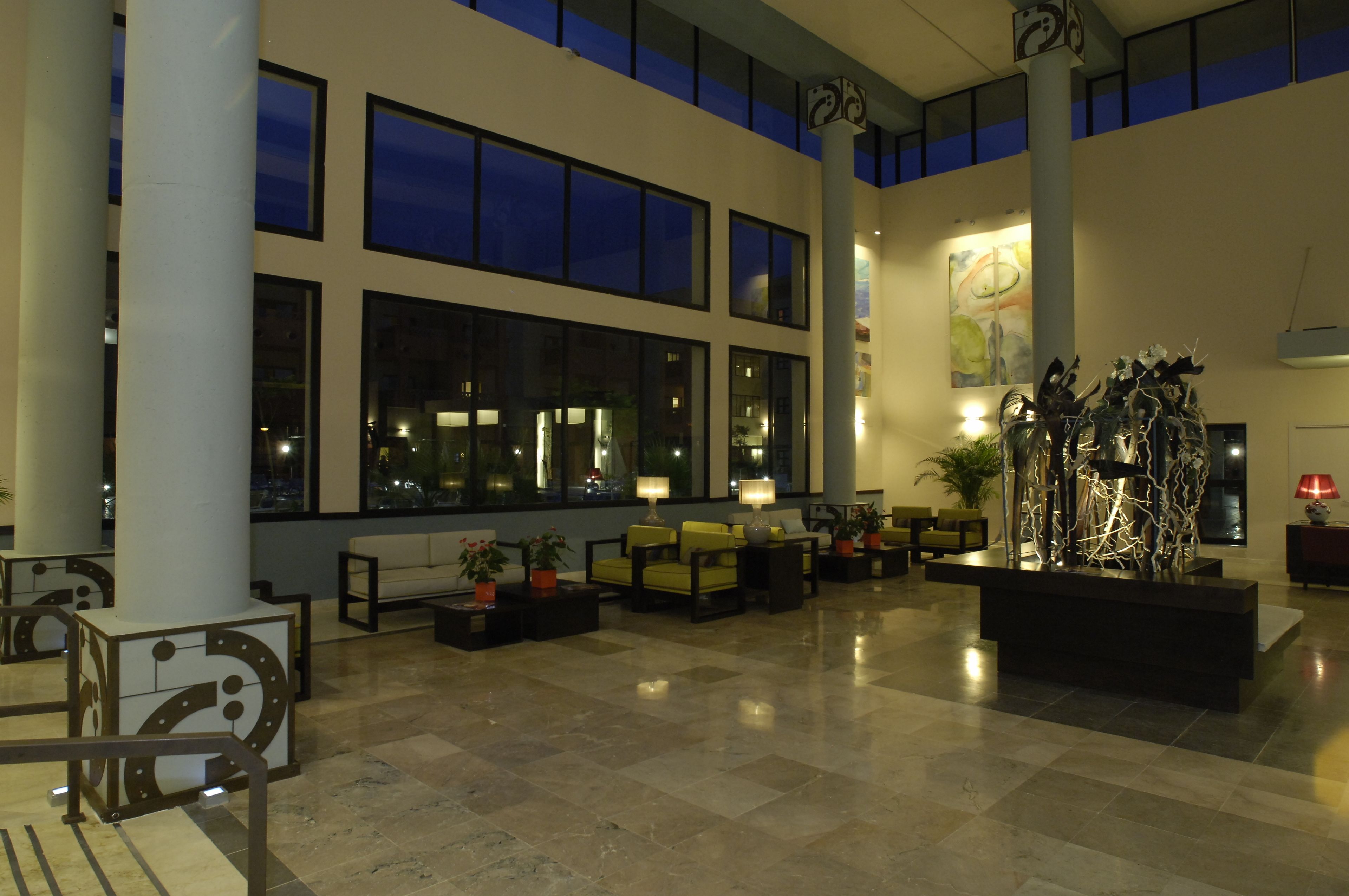A spacious lobby with high ceilings, large windows, and modern furnishings.