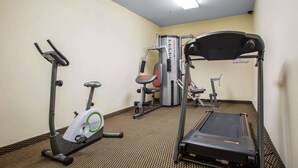 Un gimnasio con caminadora, elíptica y máquinas de pesas.