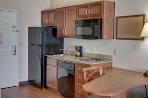 Cocina compacta con refrigerador, microondas, cafetera y un lavamanos pequeño.