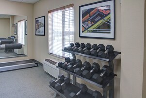 Un gimnasio con equipo de ejercicio, incluyendo cintas de correr y mancuernas, y cuadros en las paredes.