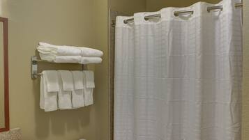 A bathroom with a shower curtain, a toilet, and towels hung on a rack.