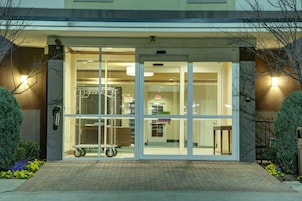 Entrada de hotel con puerta de vidrio, parquímetro y cartel que indica puerta corredera automática.
