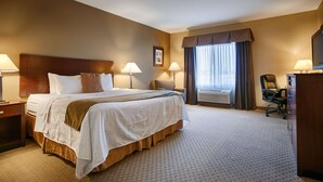 A hotel room with a large bed, two bedside lamps, a chair, a desk, and a window with curtains. - Best Western Plus Montezuma Inn & Suites (Las Vegas)