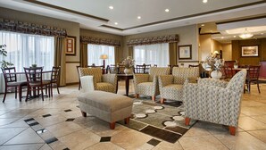 A spacious living room with a large sofa set, a dining area with wooden chairs, and a kitchen area with a counter and chairs. - Best Western Plus Montezuma Inn & Suites (Las Vegas)