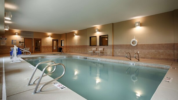 A swimming pool with clear water, metal ladders, and lounge chairs. - Best Western Plus Montezuma Inn & Suites (Las Vegas)