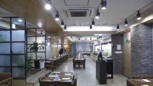 Een restaurant met meerdere eettafels, stoelen en een toonbank.