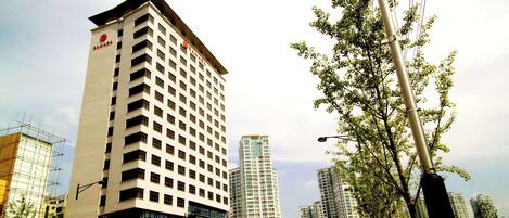 A tall hotel with a modern design, multiple floors, and a prominent logo on the side.
