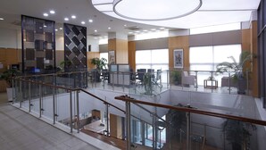 Een modern interieur met glazen balustrade, een trap en uitzicht op de lobby.