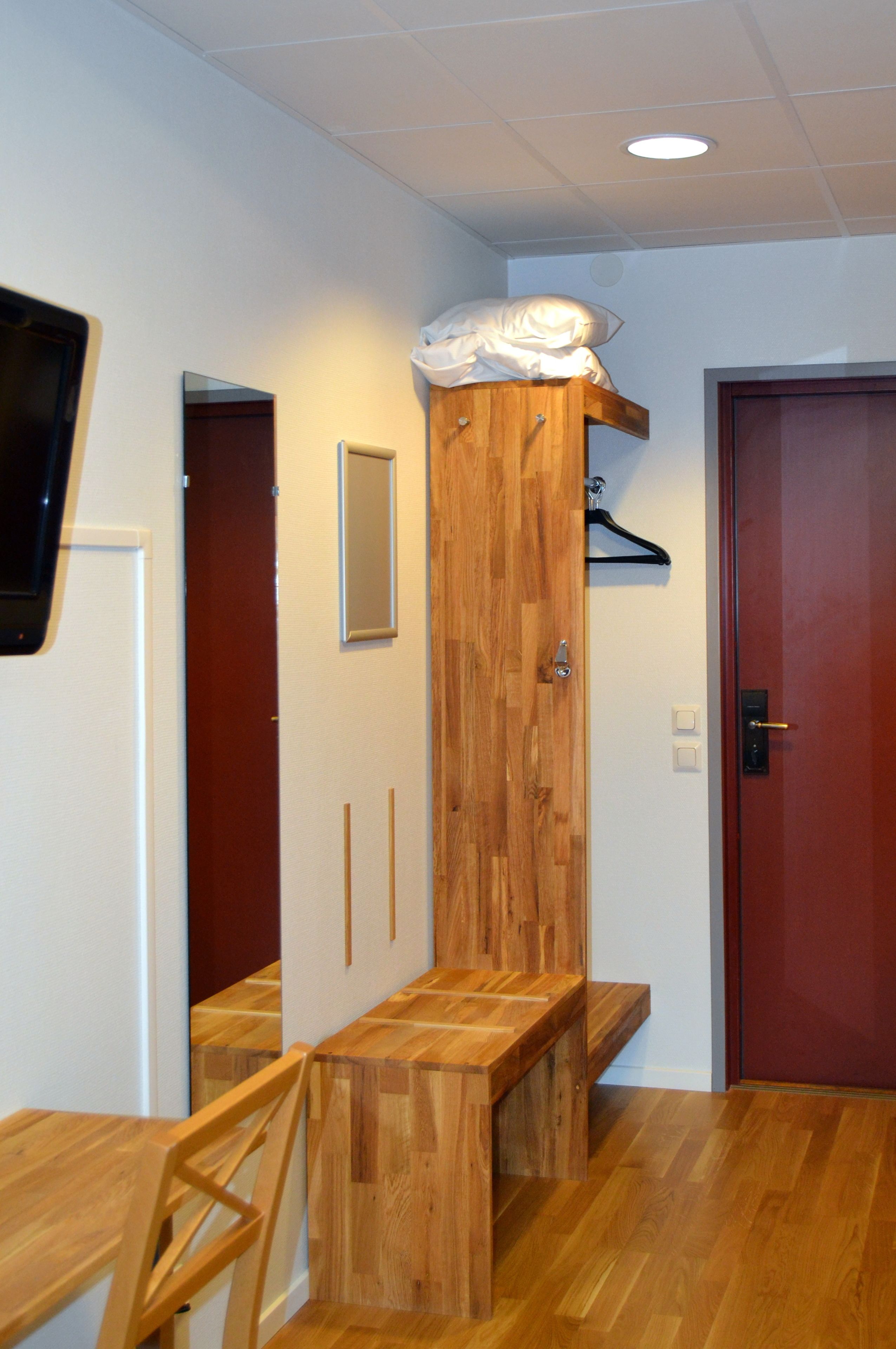 A hallway with a wooden bench, a coat rack, and a door.