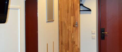 A hallway with a wooden bench, a coat rack, and a door.