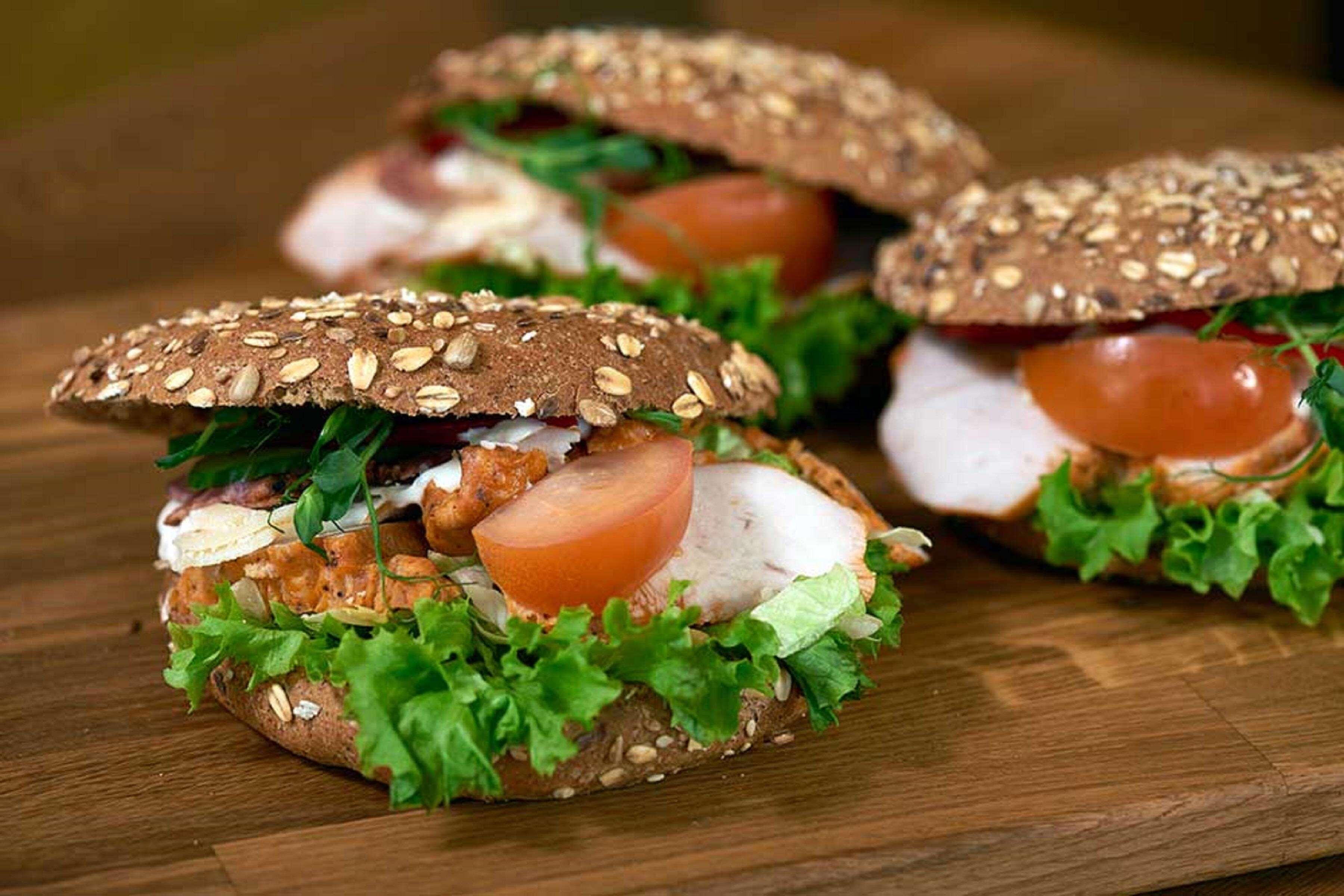 A sandwich with a sesame seed bun, lettuce, tomato, and chicken.