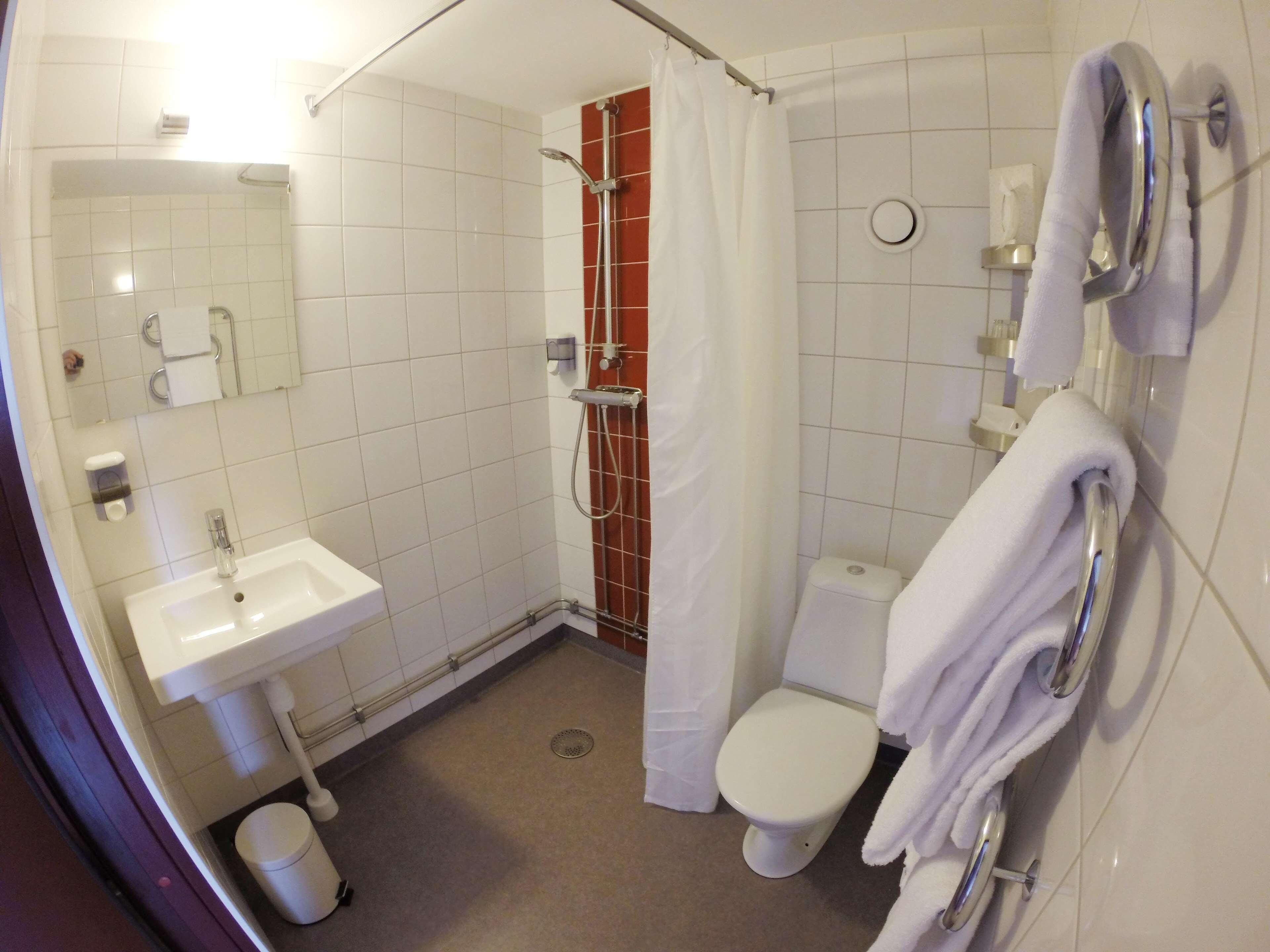 A bathroom with a white sink, toilet, and shower.
