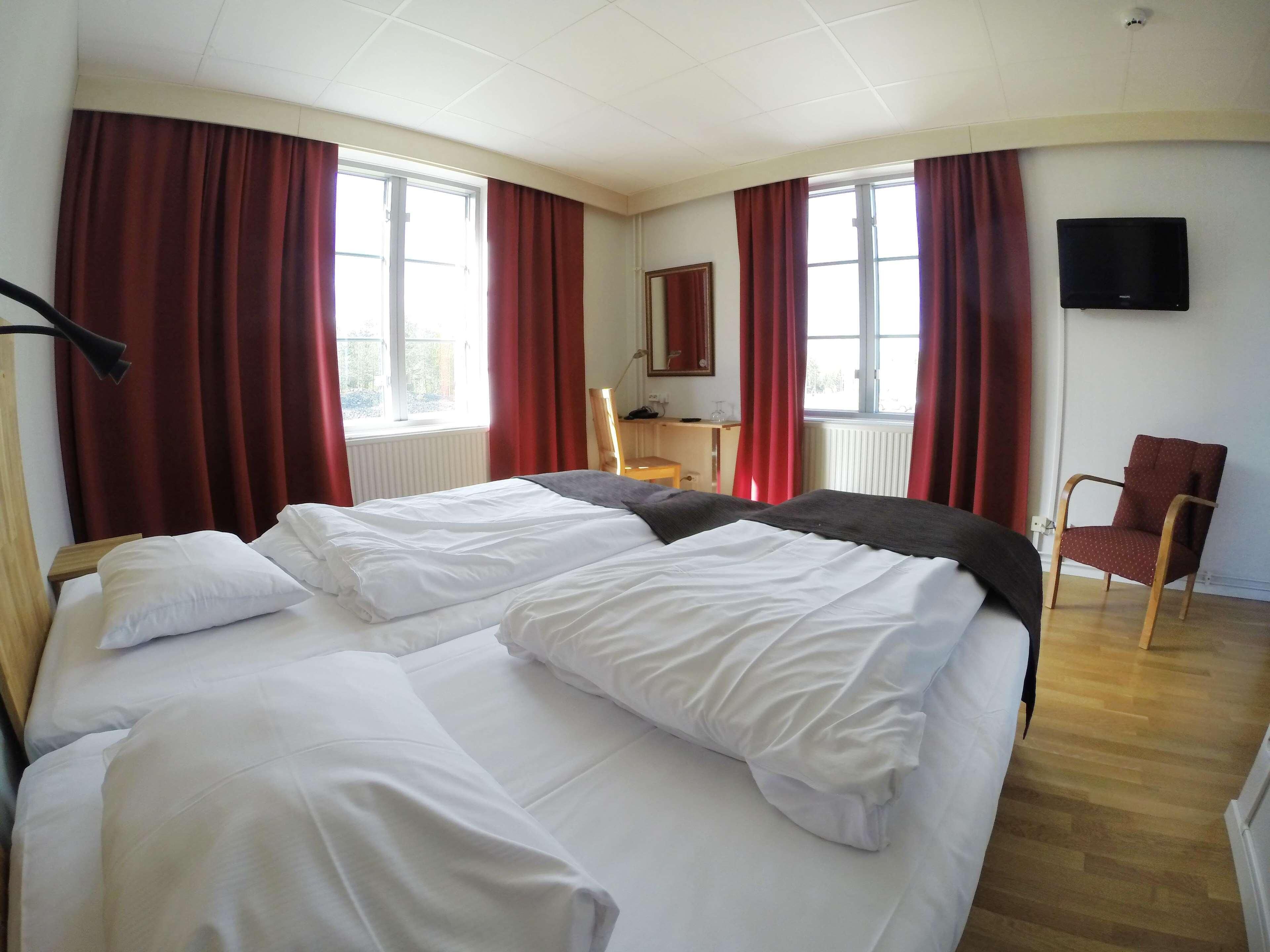 Habitación de hotel con dos camas, un escritorio, una silla y un televisor.