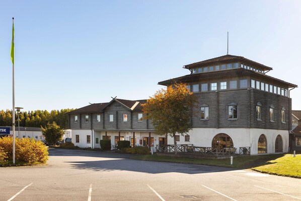 A two-story building with a central tower, a parking lot, and a flagpole.