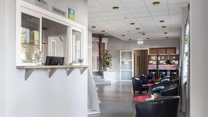 A reception area with a counter, chairs, and a staircase leading to another floor. - Dalhall Hotell (Åmål)