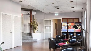 A lobby with a staircase, seating area, and vending machines. - Dalhall Hotell (Åmål)