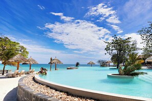 A resort pool area with lounge chairs and umbrellas, surrounded by a pebble-lined edge. - Bawe Tropical Island (Bawe Island)