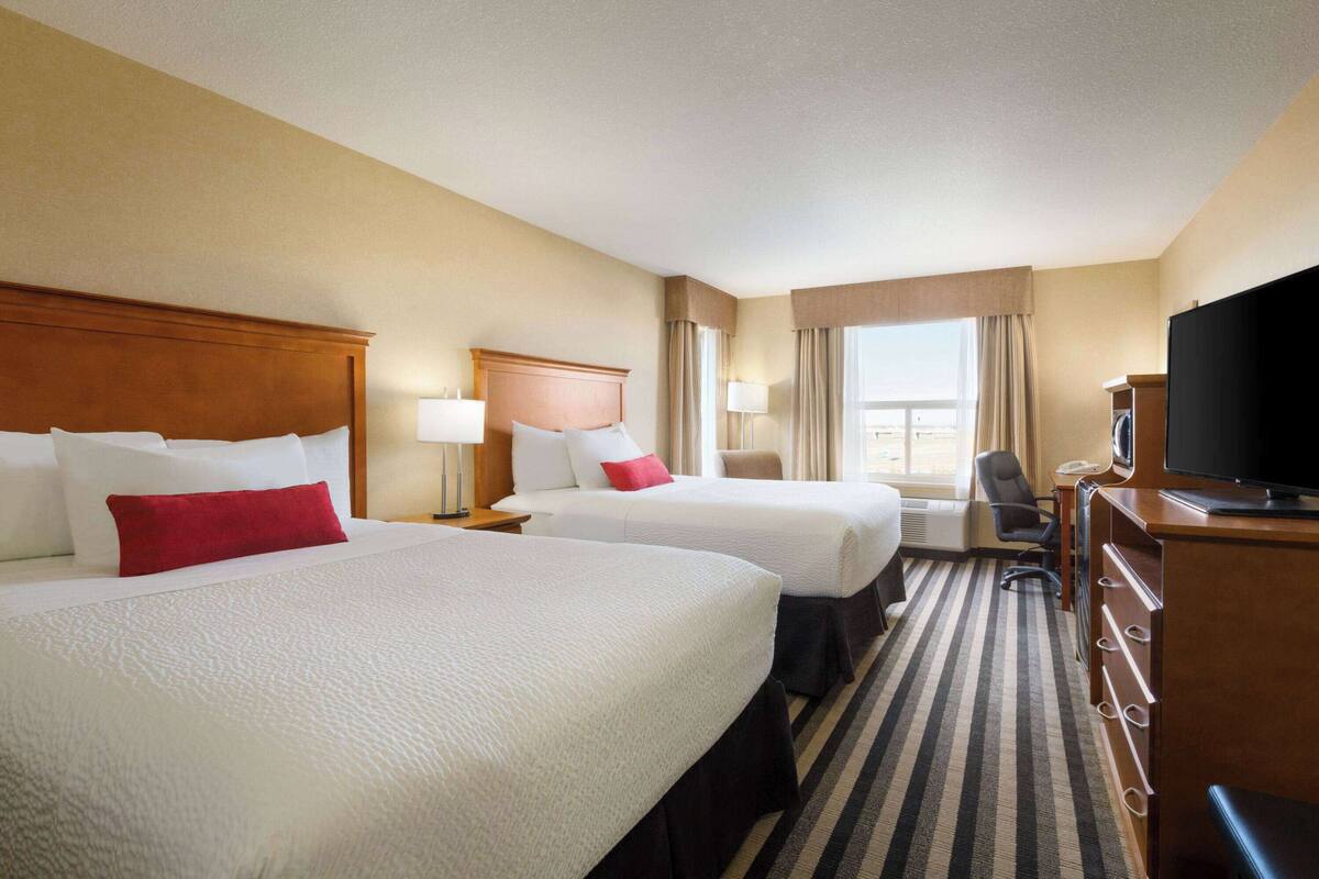 Habitación de hotel con dos camas, televisor, escritorio y una silla.