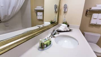 Une salle de bain d’hôtel avec un grand miroir, un lavabo, des toilettes et un porte-serviettes.