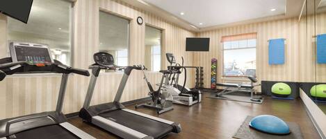A gym with treadmills, exercise bikes, and a rowing machine.