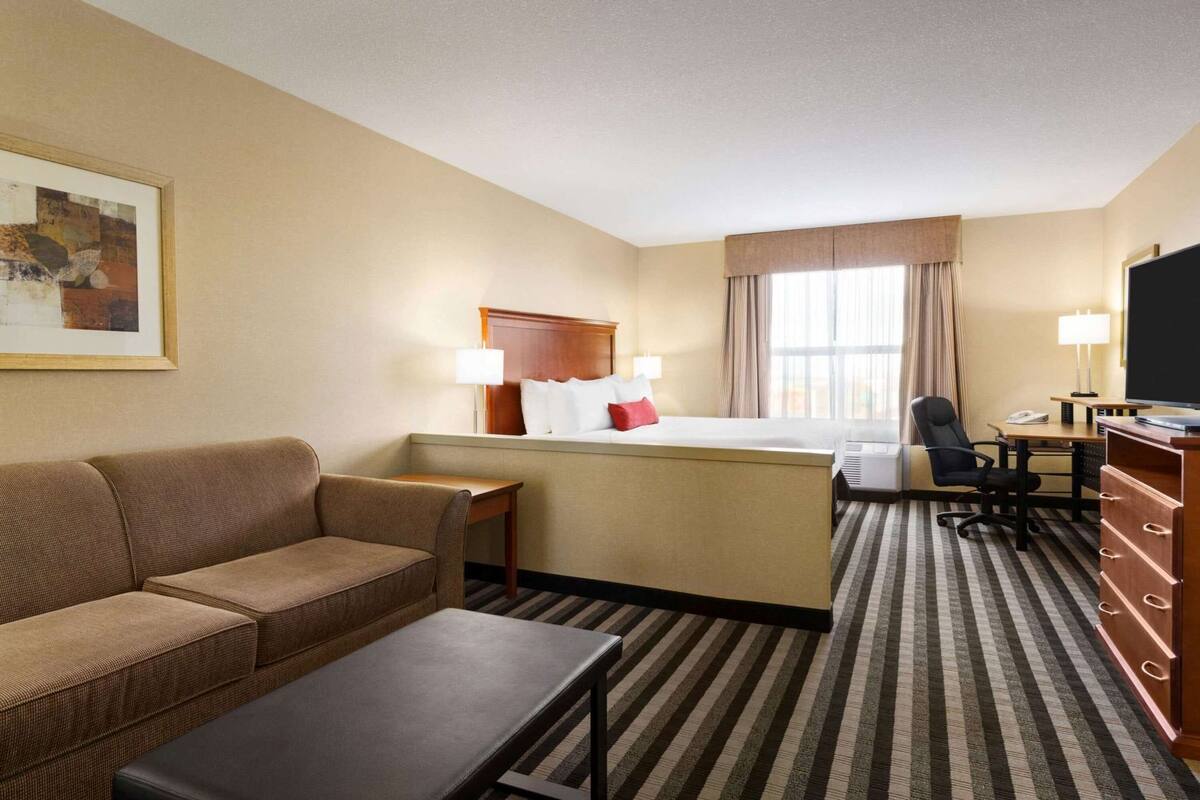 Una habitación de hotel con sofá, cama, escritorio, silla y televisión.
