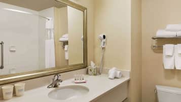 Un baño de hotel con lavamanos, espejo, toallero y retrete.